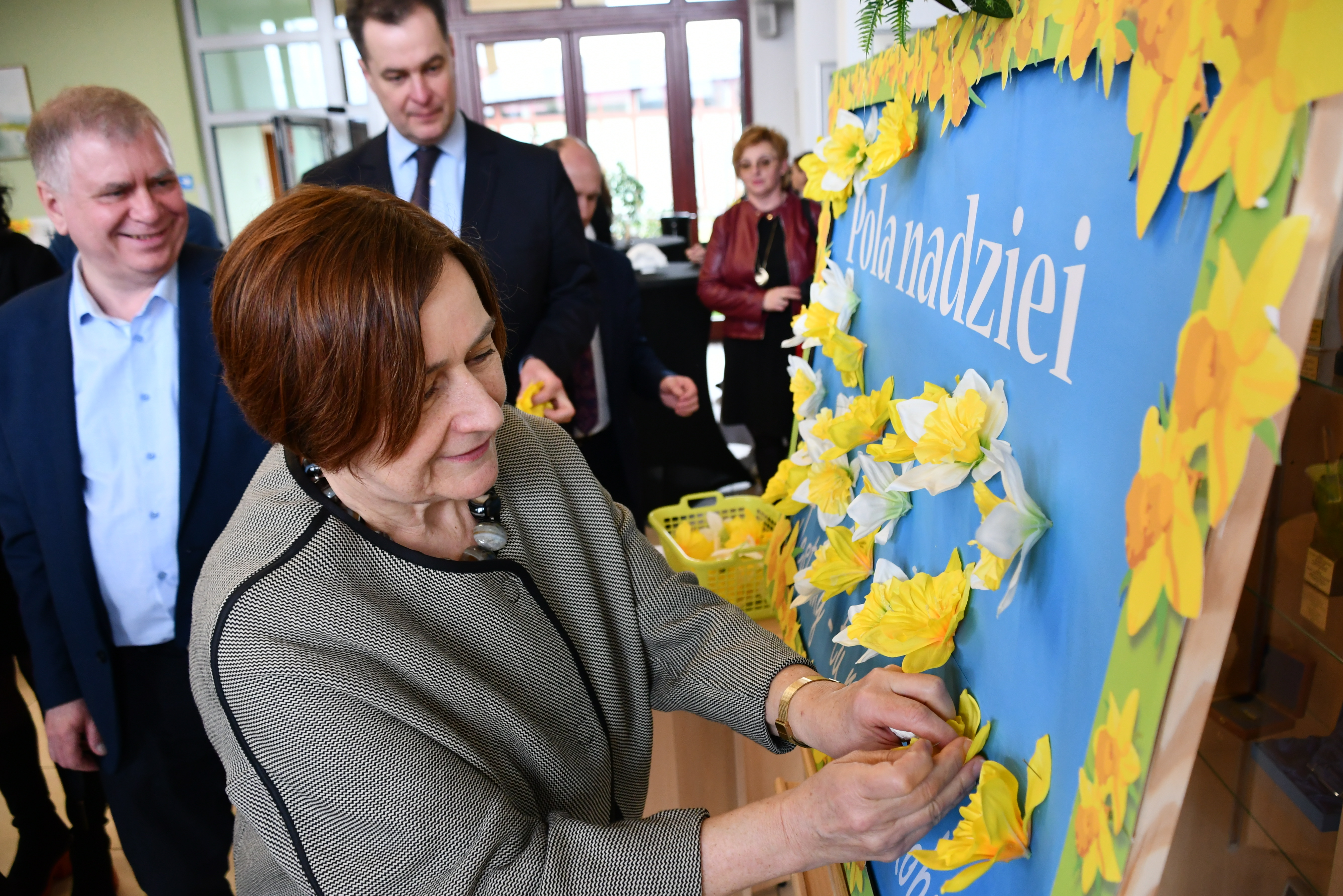 Wicestarosta i starosta wpinając bibułkowe żonkile do tablicy z napisem Pola Nadziei