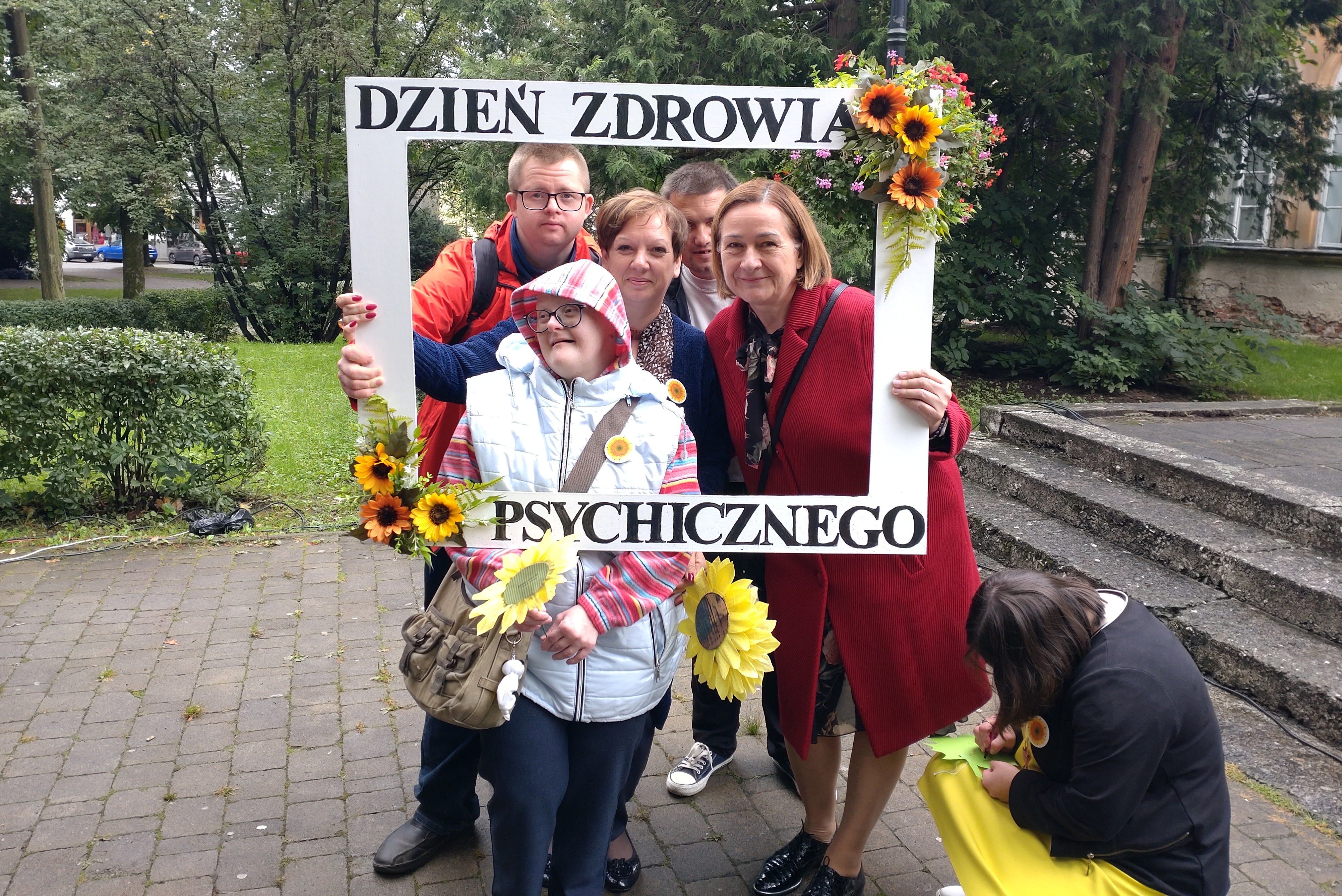 W białej ramce z napisem Dzień Zdrowia Psychicznego pozują do zdjęcia podopieczni kęckiej placówki wraz z członkinią zarządu powiatu.