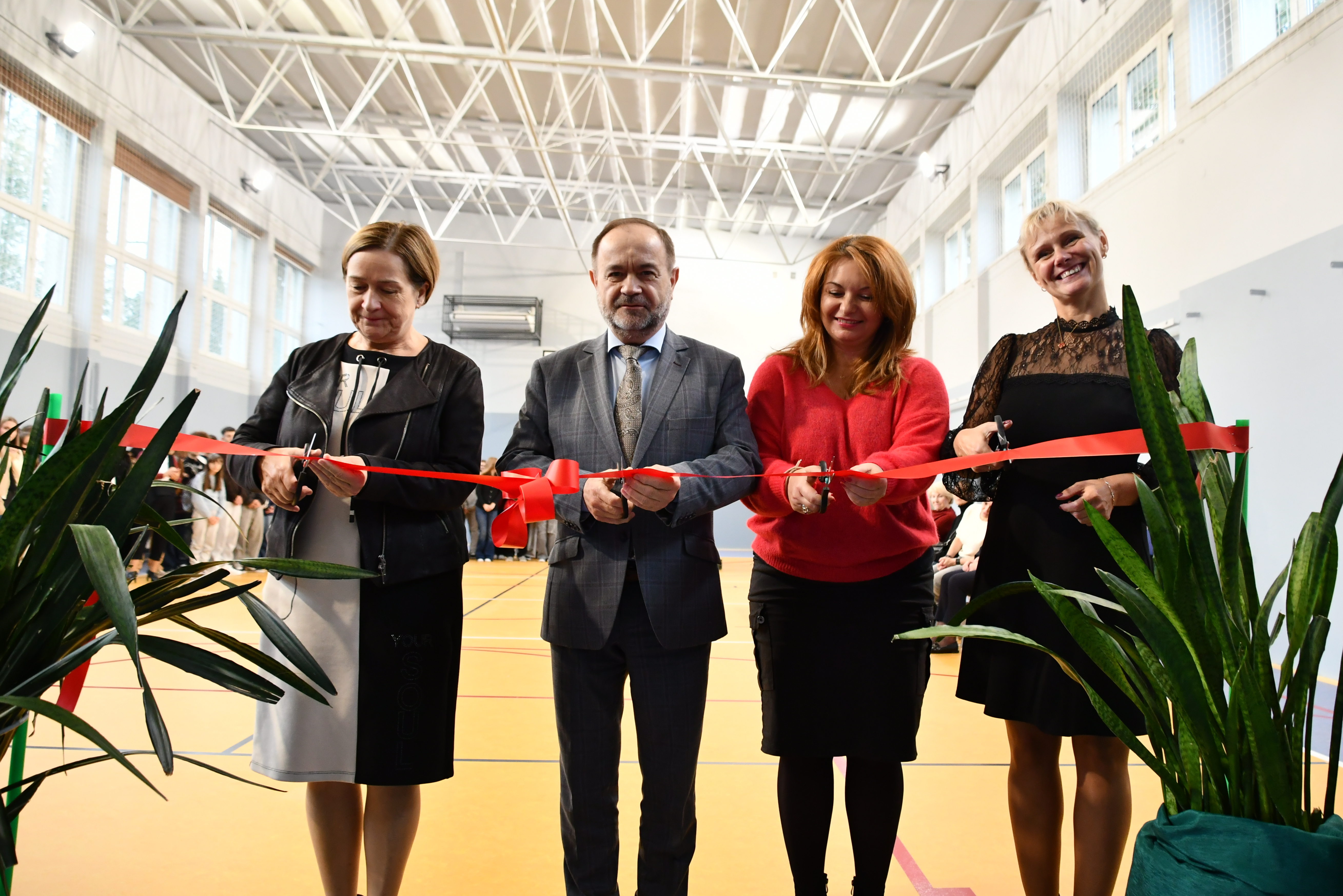 Włodarze Powiatu i dyrektorka szkoły przecinają wstęgę i w symboliczny sposób otwierając salę gimnastyczną po remoncie