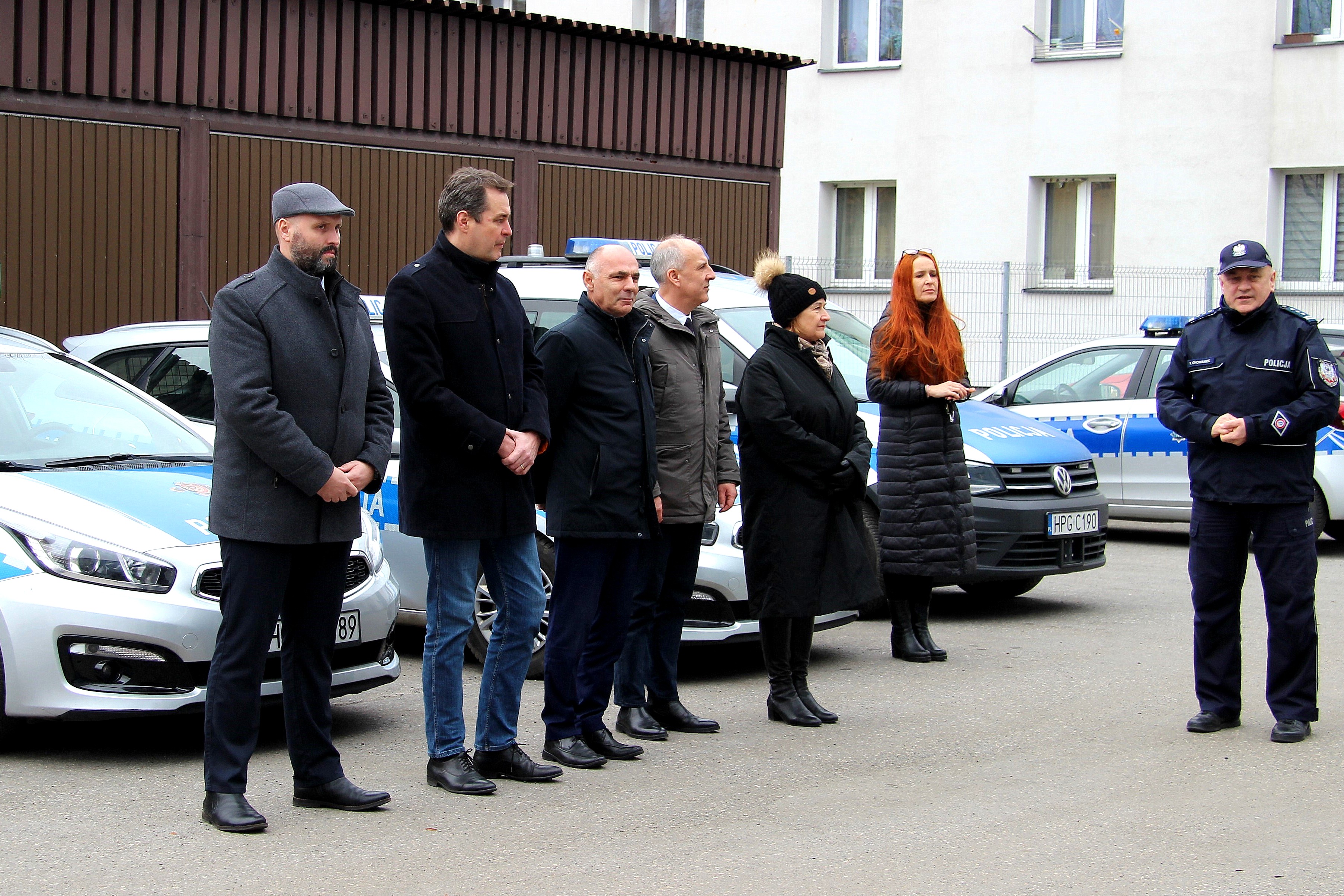 Pamiątkowe zdjęcie włodarzy wraz z komendantem powiatowym Policji na tle nowych radiowozów