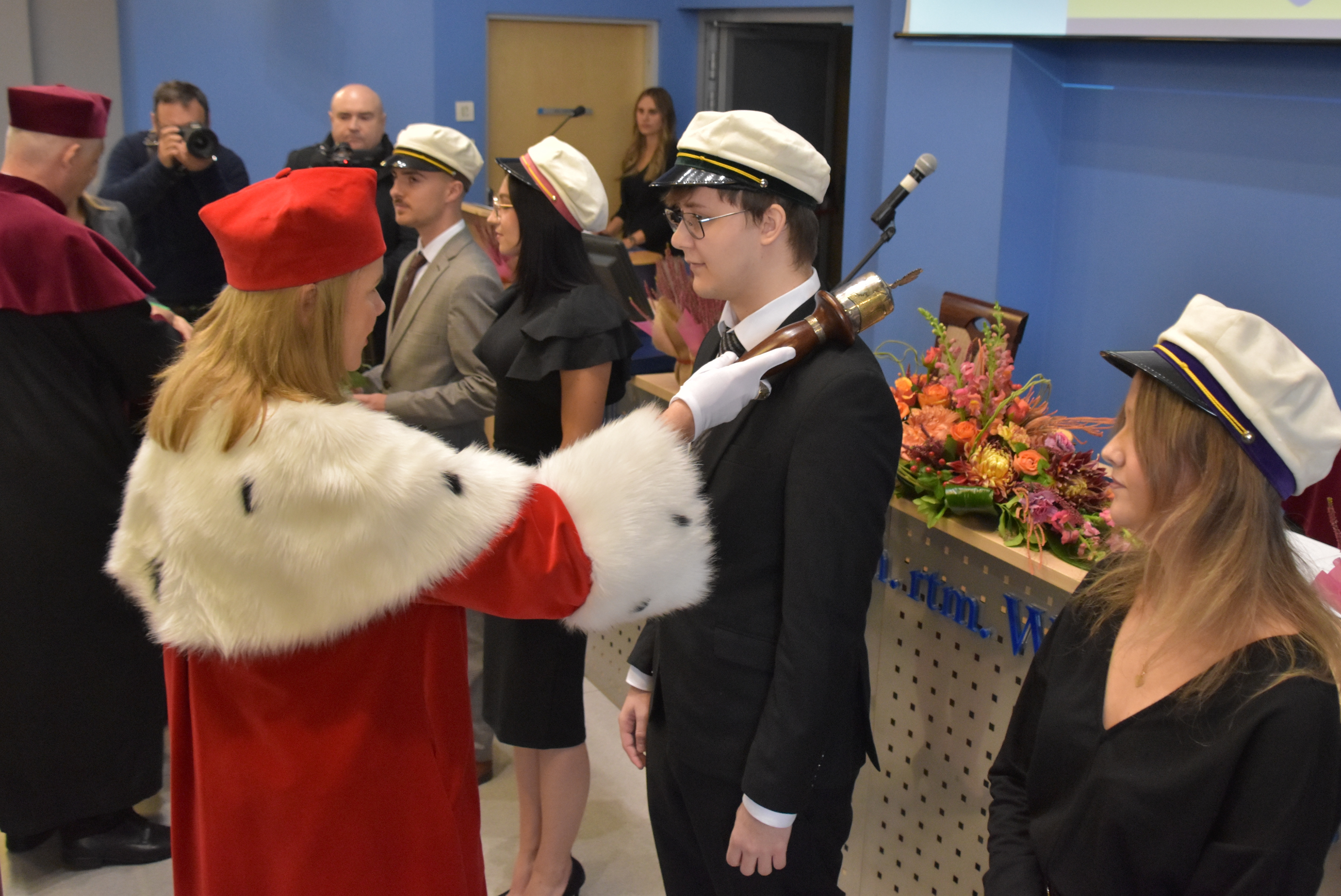 Pani rektor pasuje żaka na pełnoprawnego studenta i wręcza mu indeks