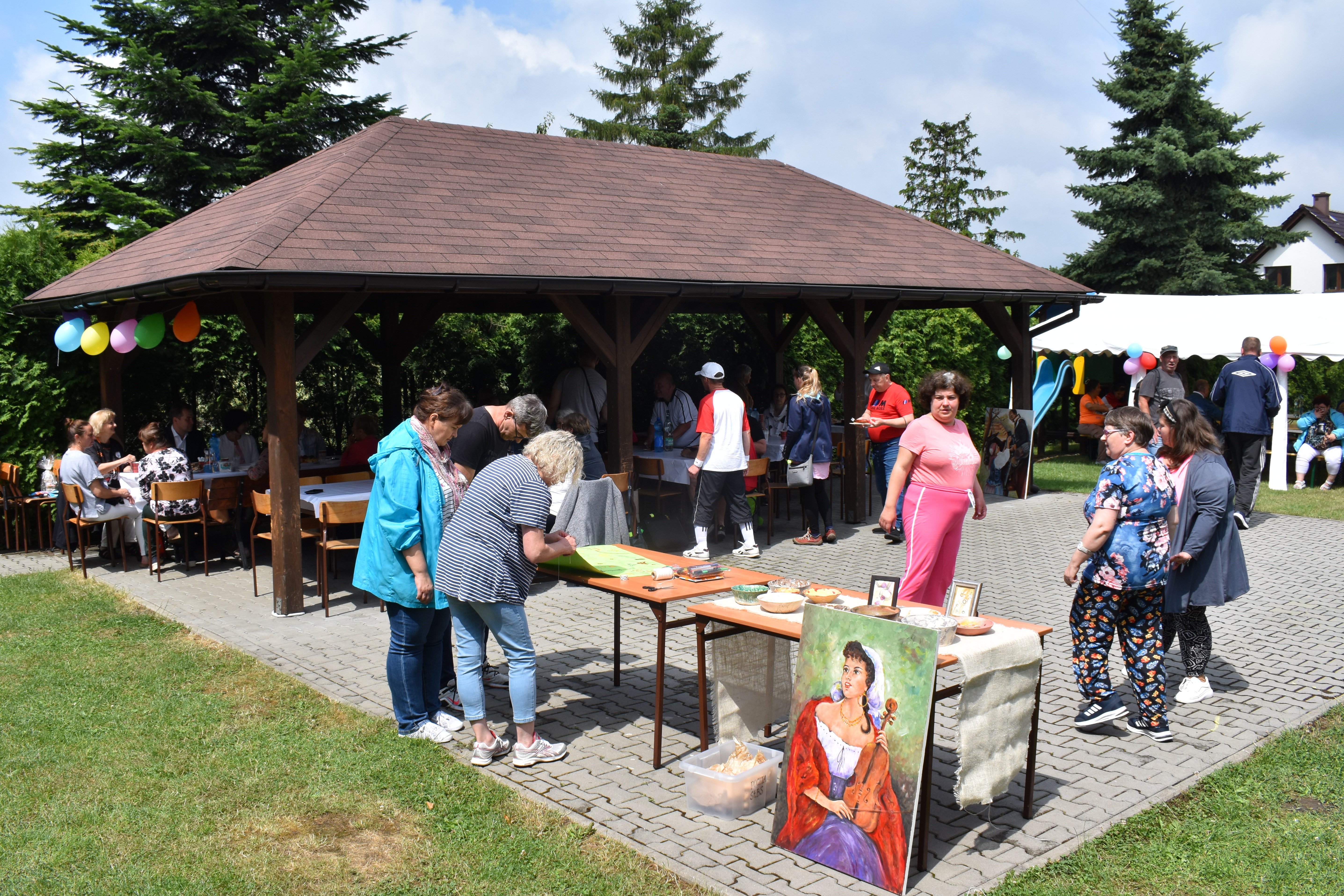 Piknik integracyjny na terenie Domu Ludowego w Babicach. Na zdjęciu widać fragment altany i uczestników imprezy