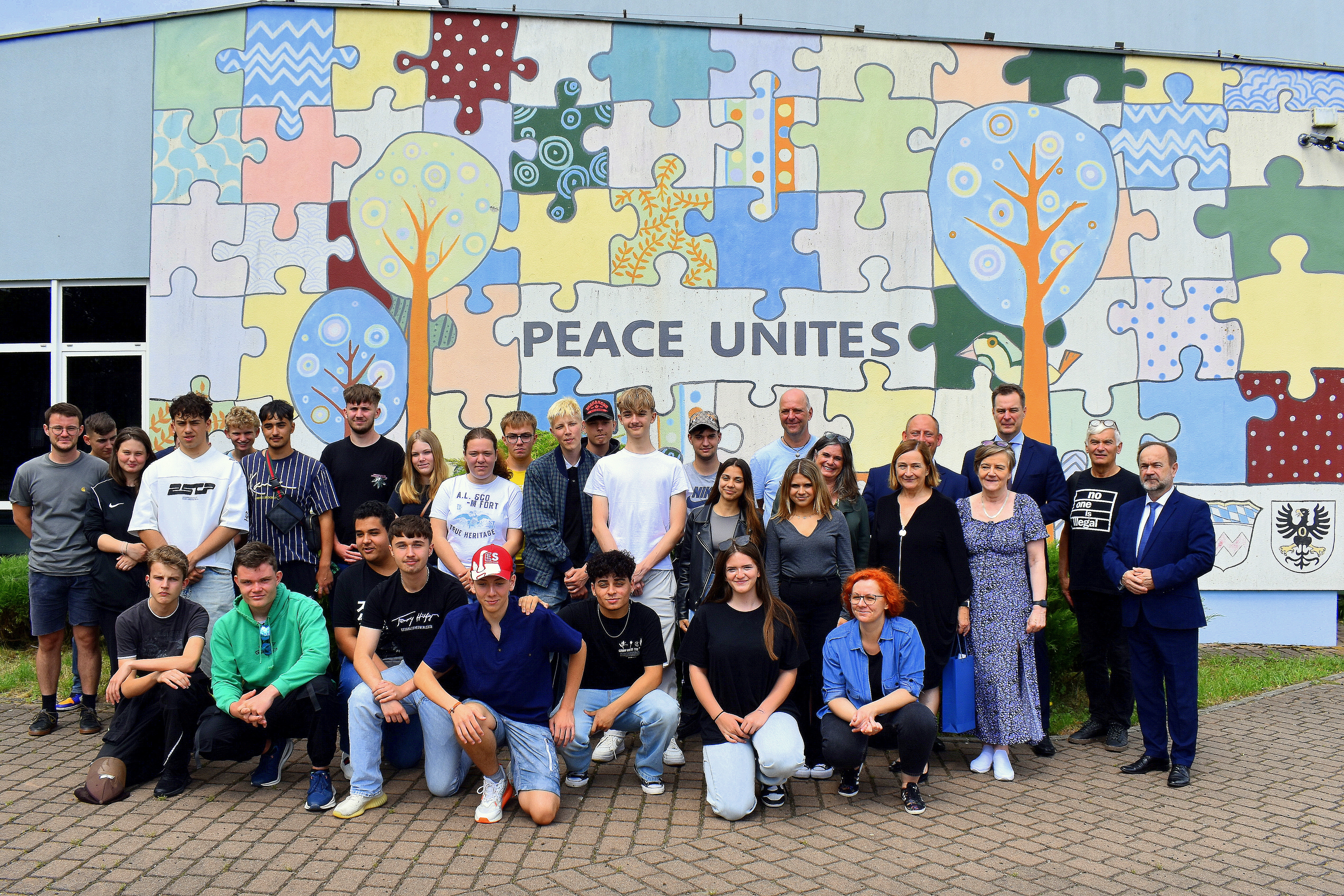 Na tle muralu Peace Unites pozuje do pamiątkowego zdjęcia grupa młodzieży z ośrodka w Dachau oraz włodarze Małopolski i Powiatu Oświęcimskiego