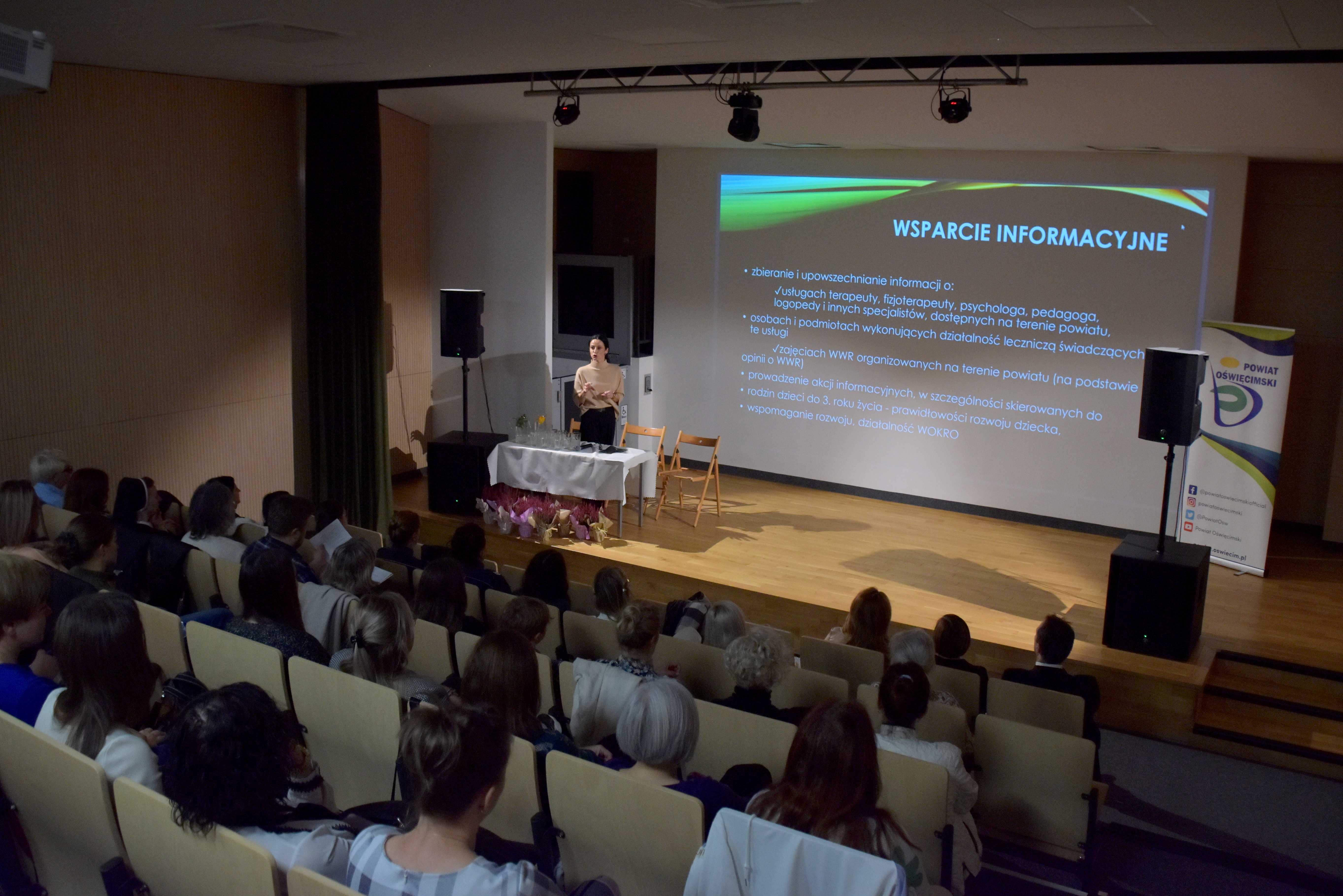Konferencja w auli SOSW, widok na prowadzącą i treść na ekranie