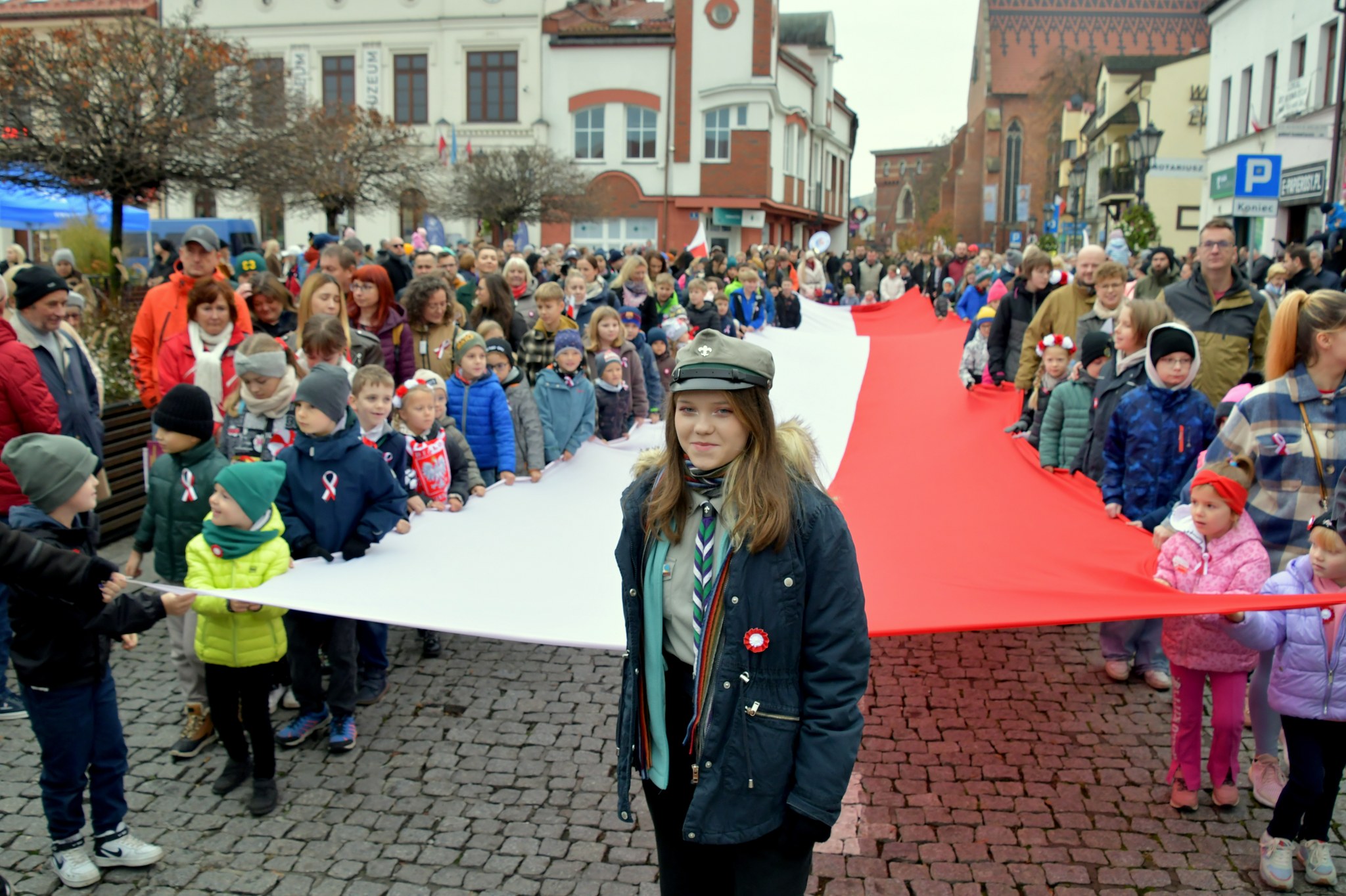 Grupa uczestników niesie długą na 20 metrów biało-czerwoną flagę
