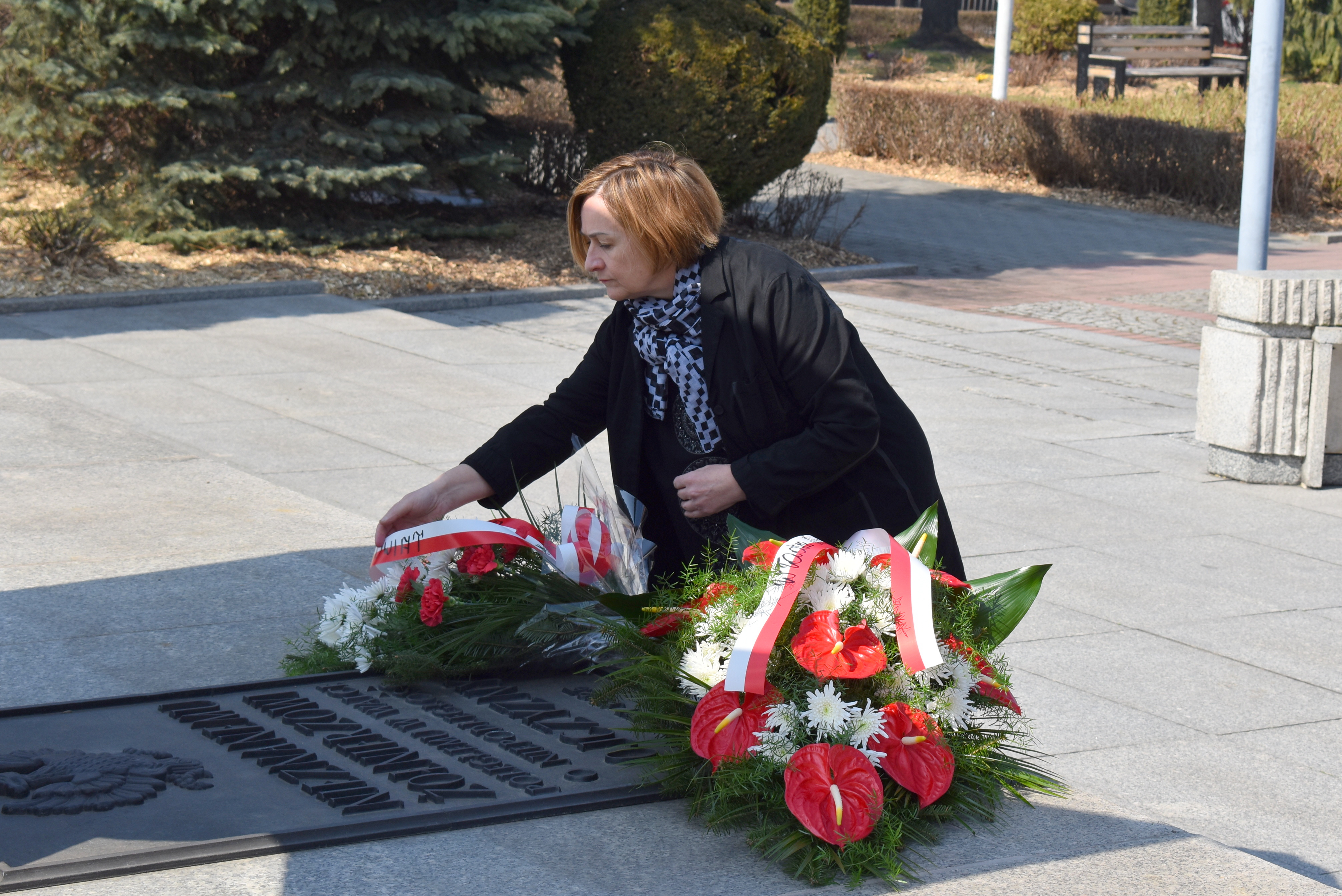 Teresa Jankowska z Zarządu Powiatu składa kwoaty na płycie Grobu Nieznanego Żołnierza w Oświęcimiu.