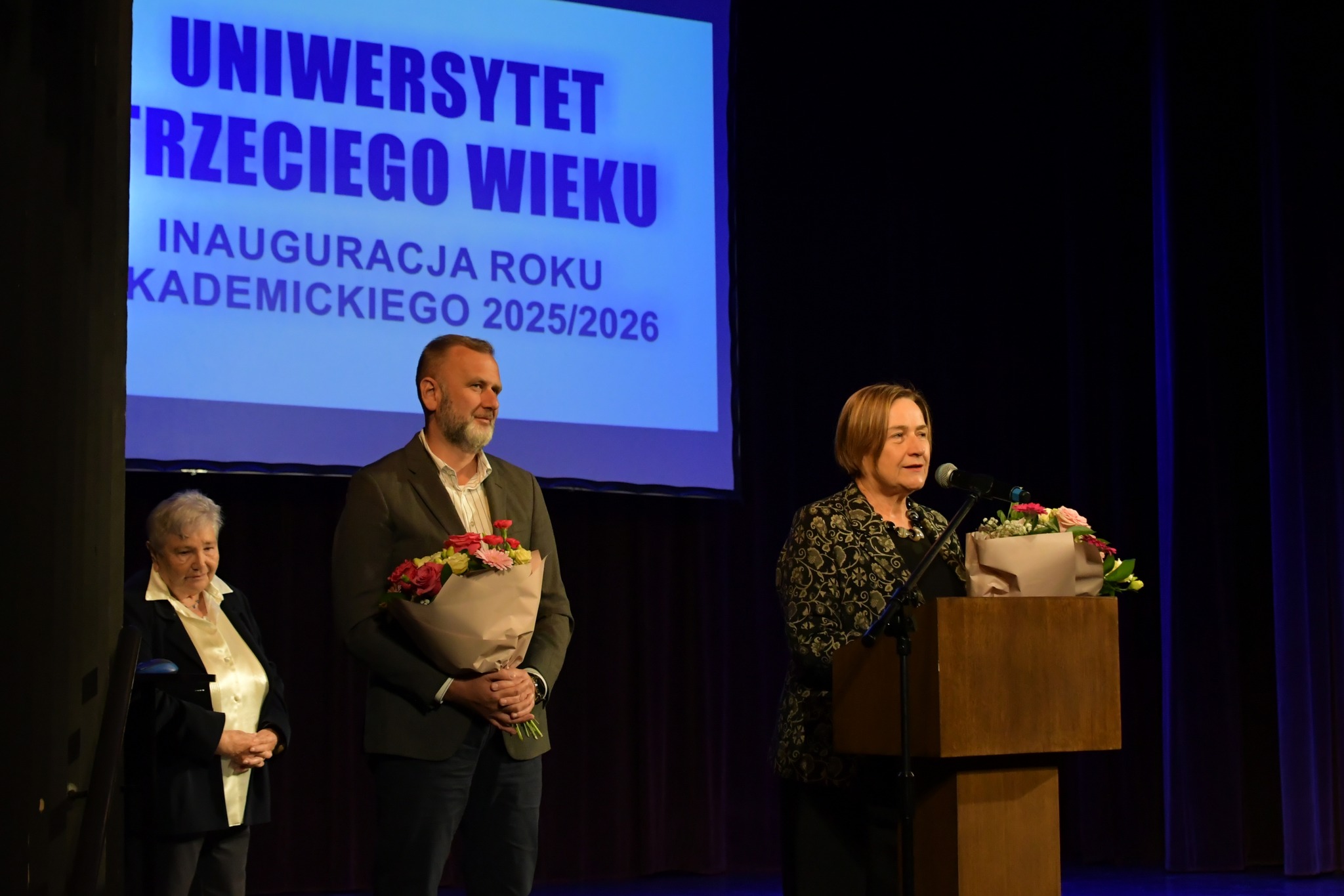 Do studentów UTW przemawia wicestarosta, obok stoi wiceprezydent miasta i koordynatorka UTW