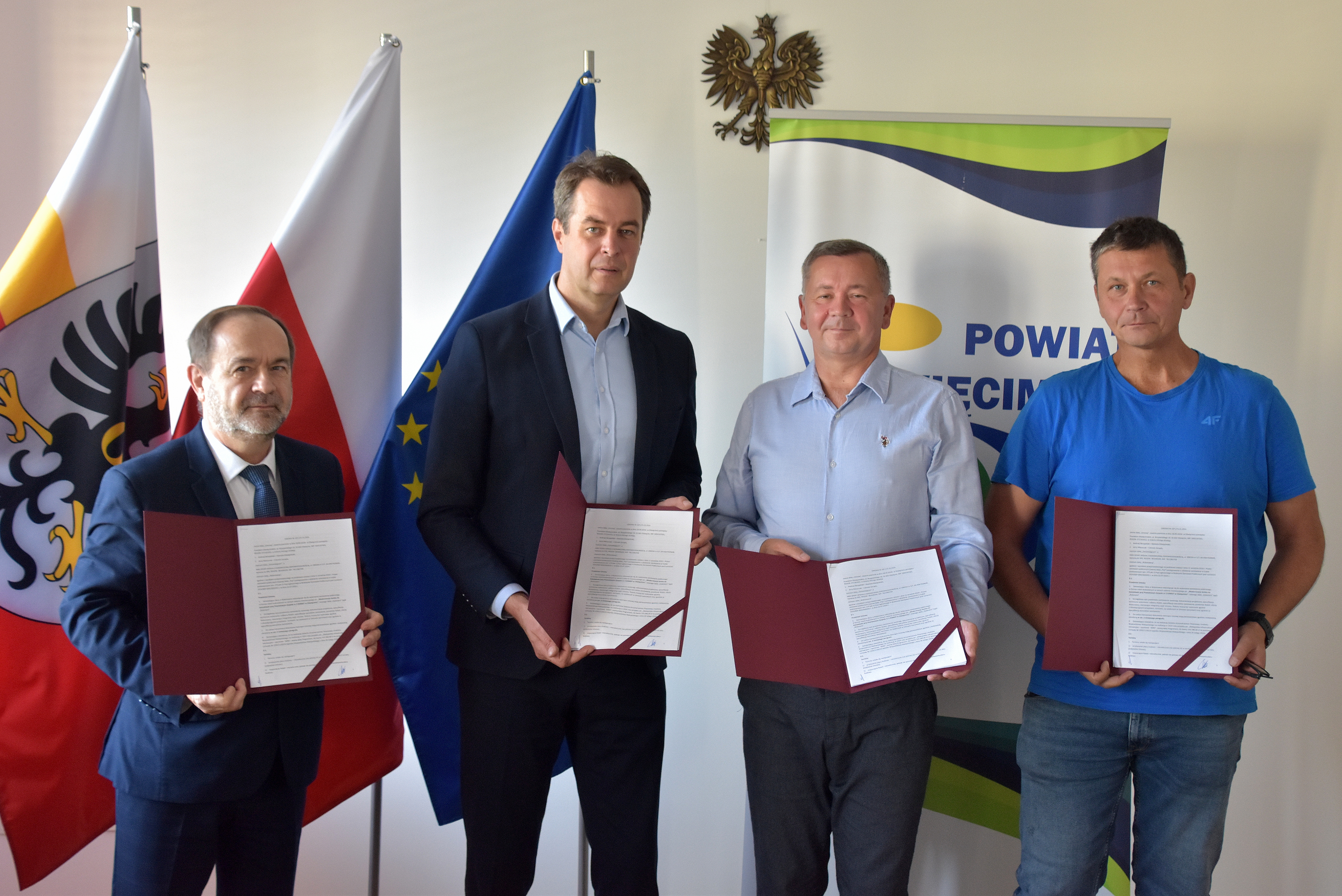 Włodarze Powiatu wraz z wykonawcami modernizacji boiska do koszyków pozują do pamiątkowego zdjęcia z umowami