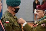 Osoba w mundurze po prawej stronie wręcza medal osobie po lewej stronie
