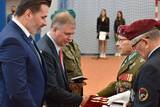 Mężczyzna w mundurze wręcza medal mężczyźnie w garniturze
